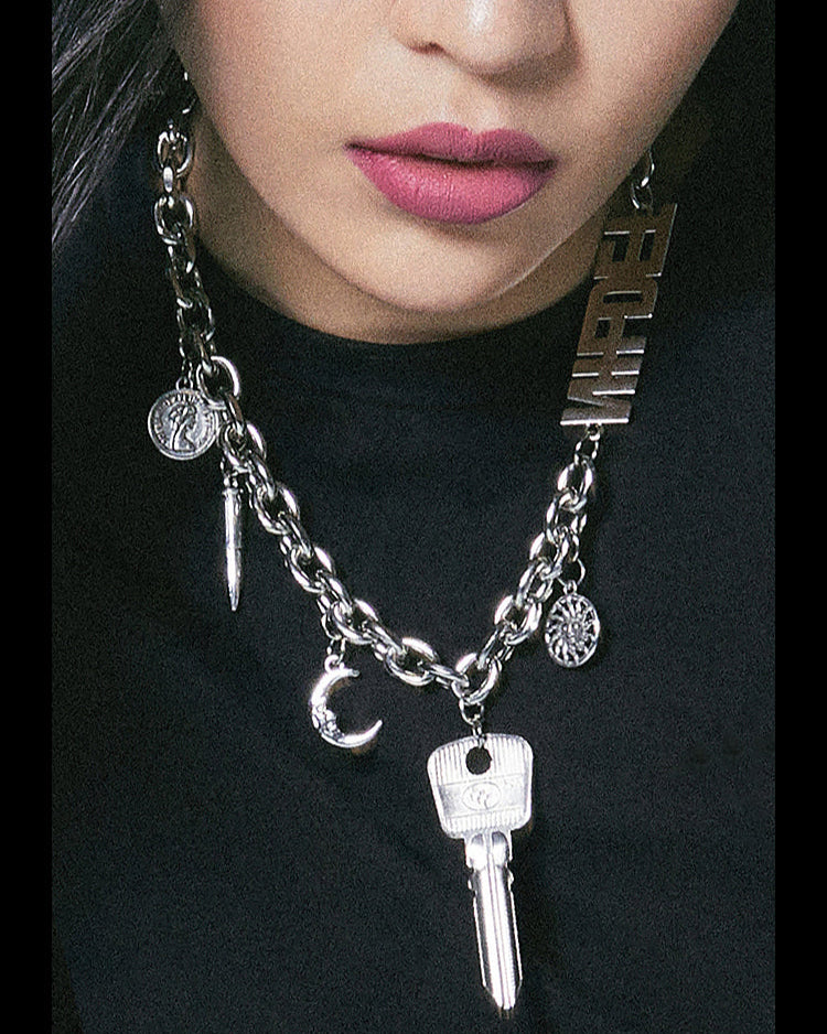 Necklace with key charm and other pendants on a black background