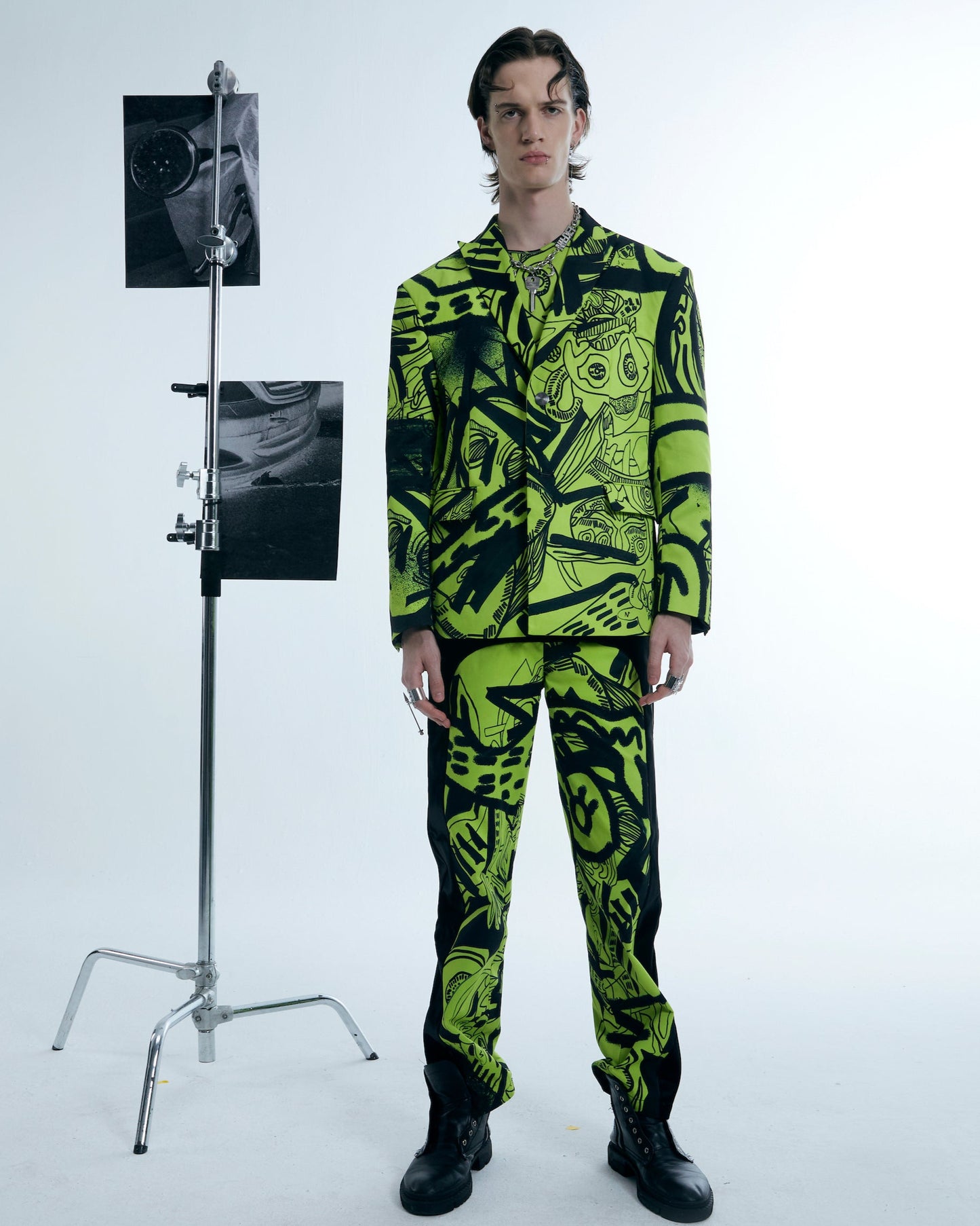 Person wearing a bright green and black patterned outfit standing next to a photo stand with images on a white background