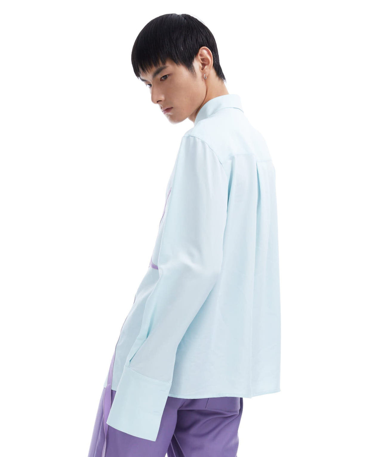 Person wearing a light blue shirt and purple pants on a white background
