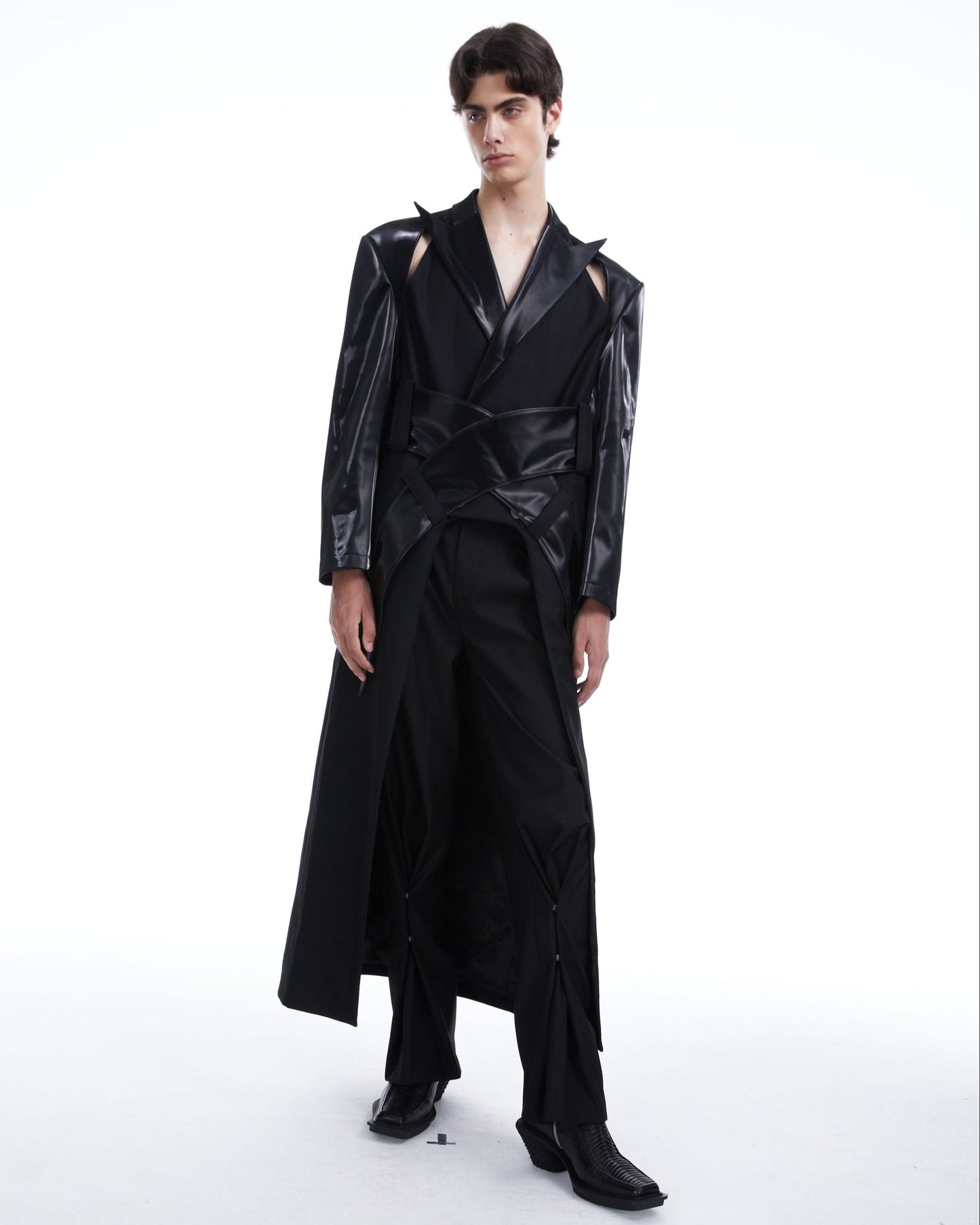 Person wearing a black outfit with a long coat on a white background