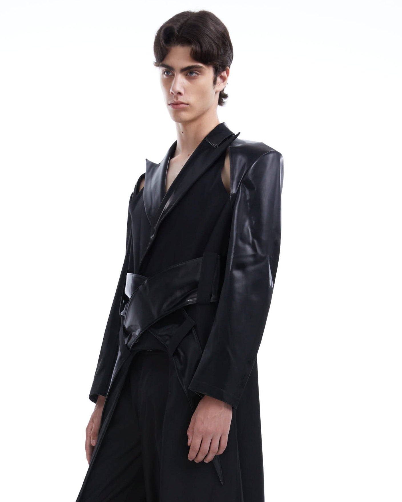 Person wearing a long black coat on a white background