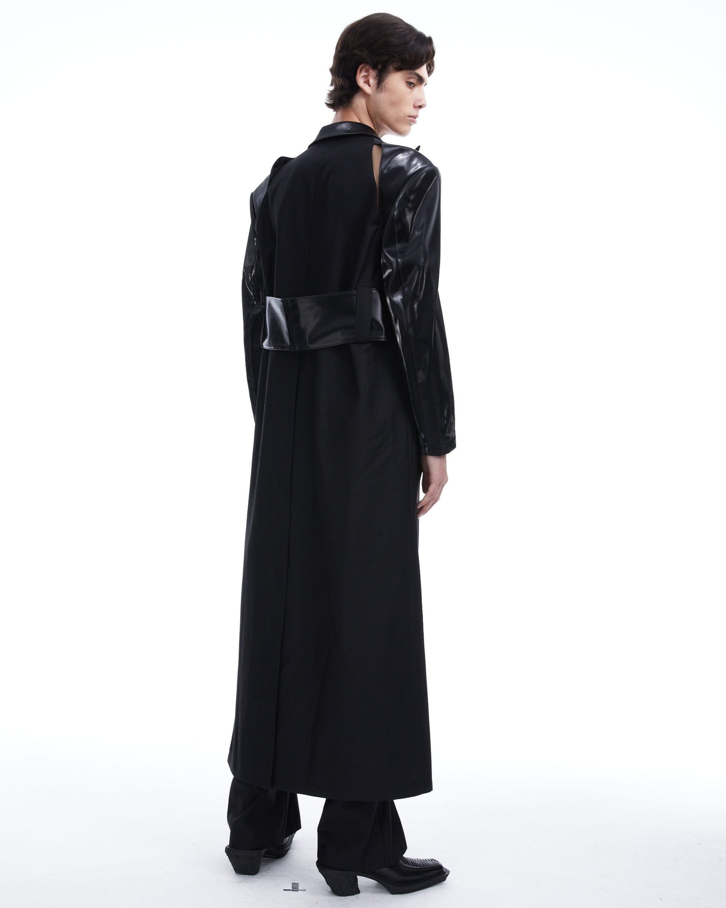 Person wearing a long black coat on a white background
