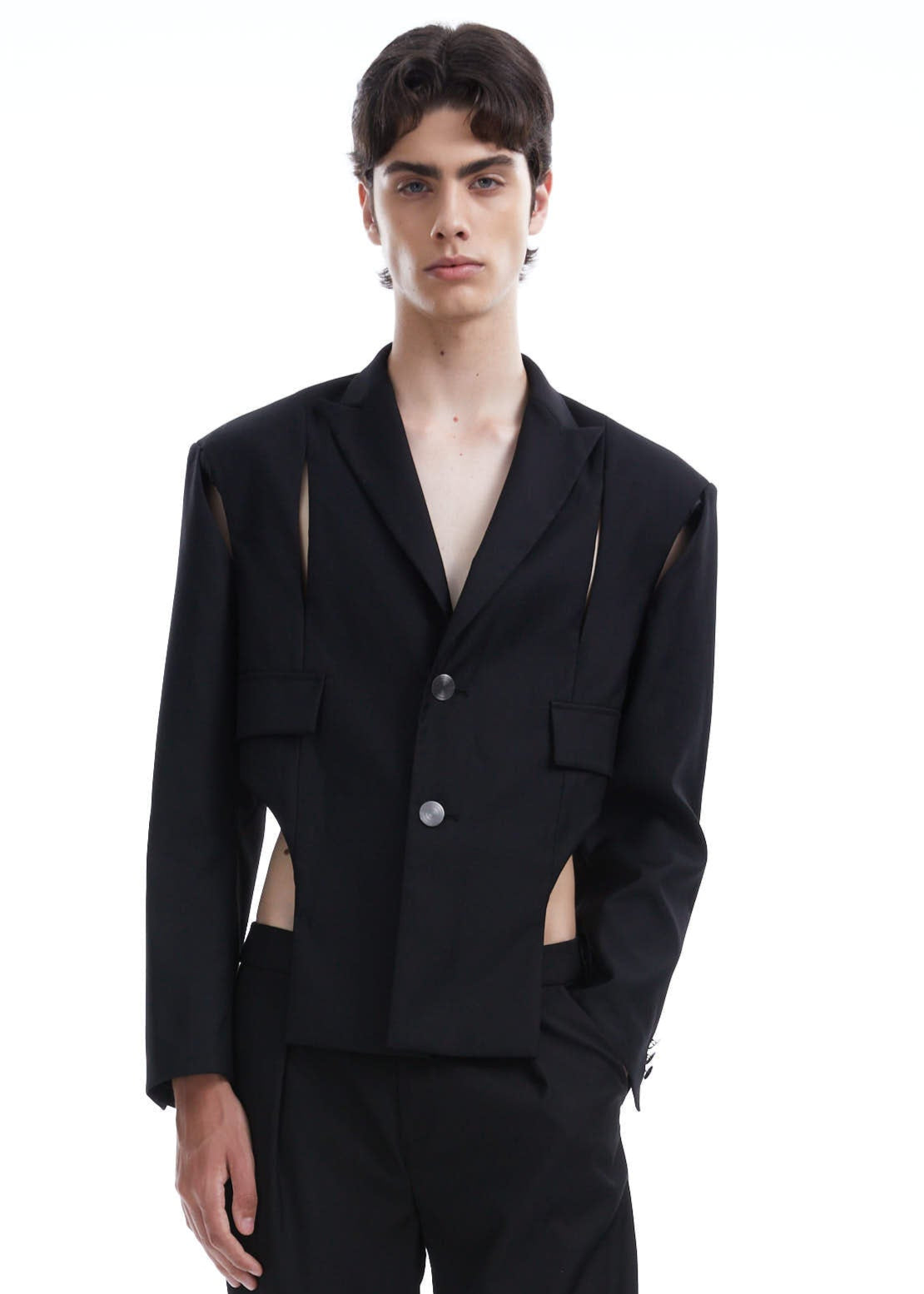 Person wearing a black suit with cut-out details on a white background