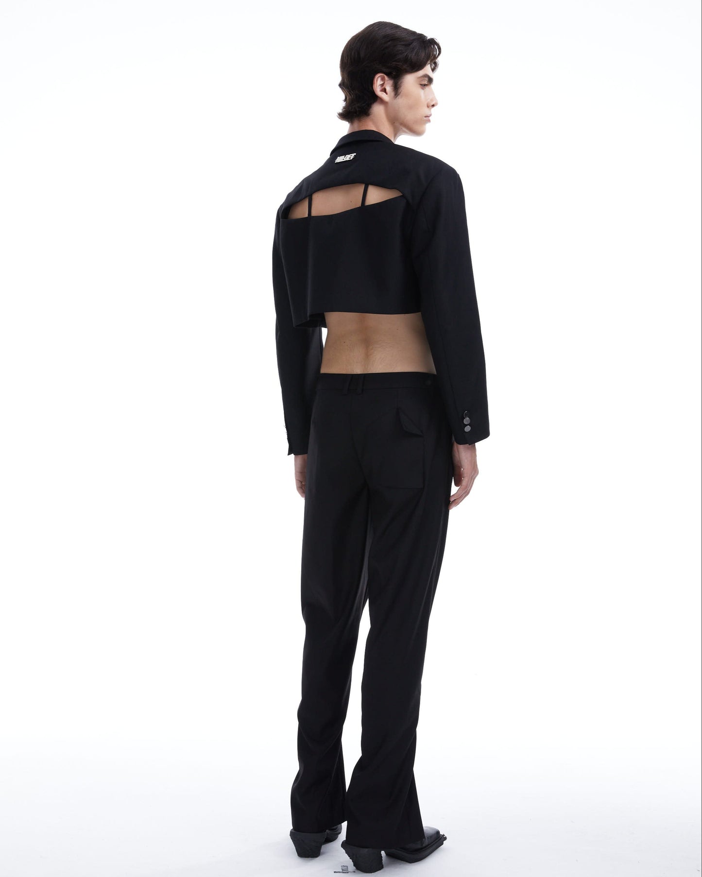 Person wearing a black outfit with sheer details on a white background