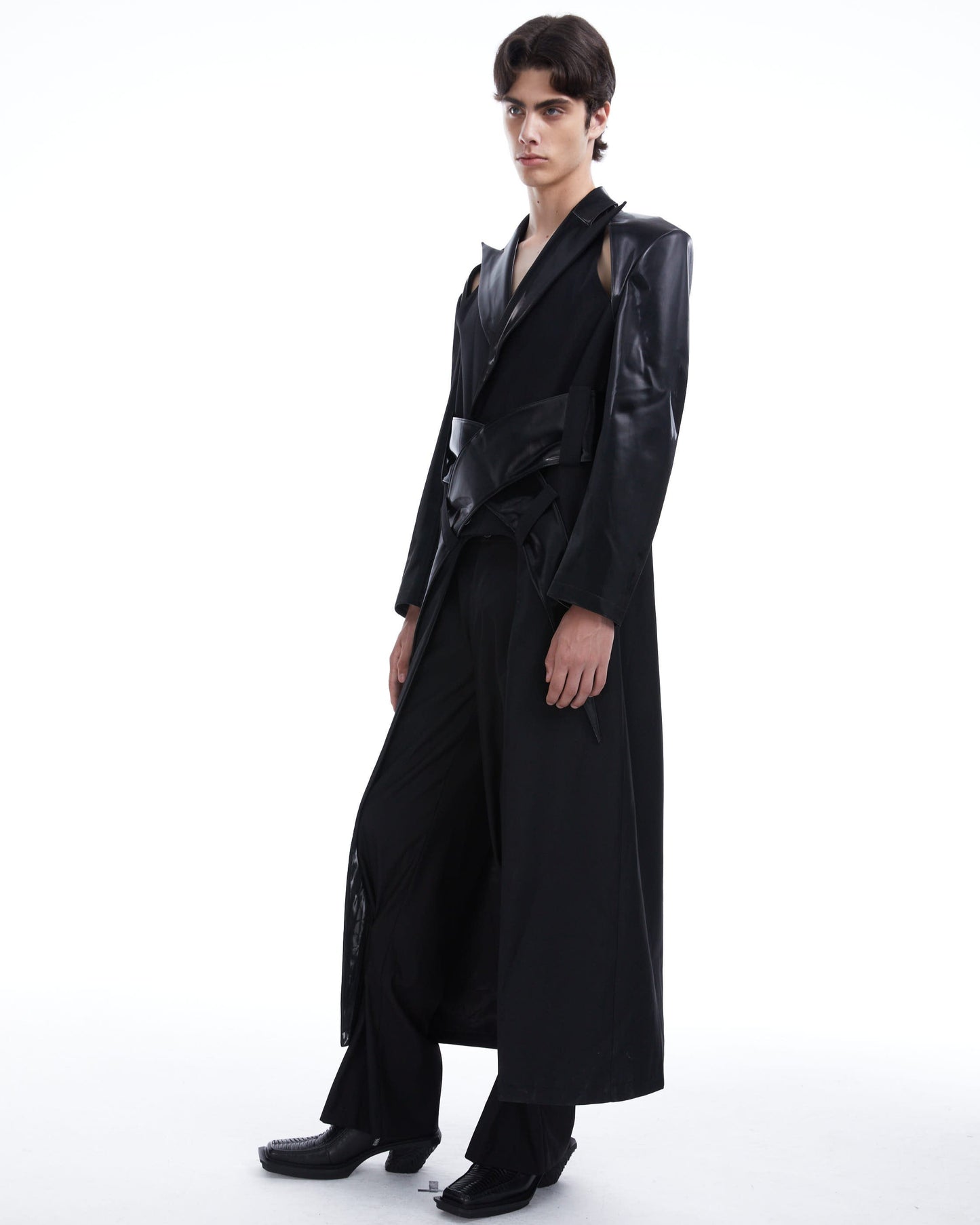 Person wearing a long black coat on a white background