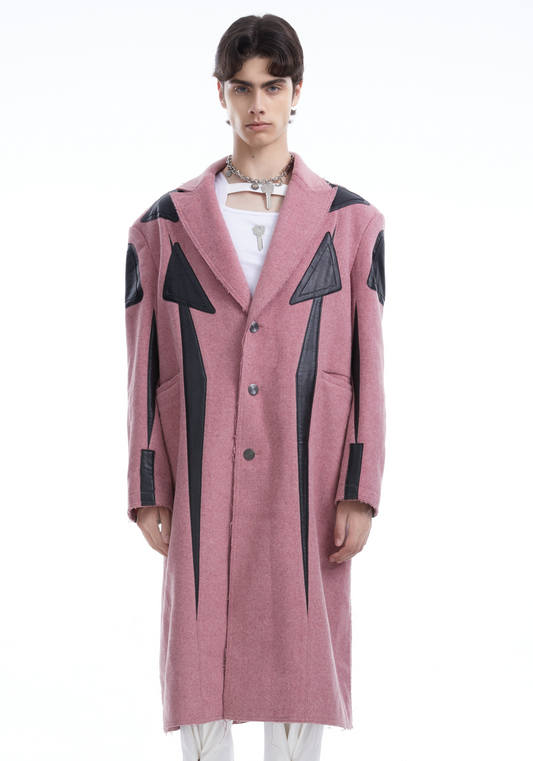 Person wearing a pink coat with black geometric patterns on a white background