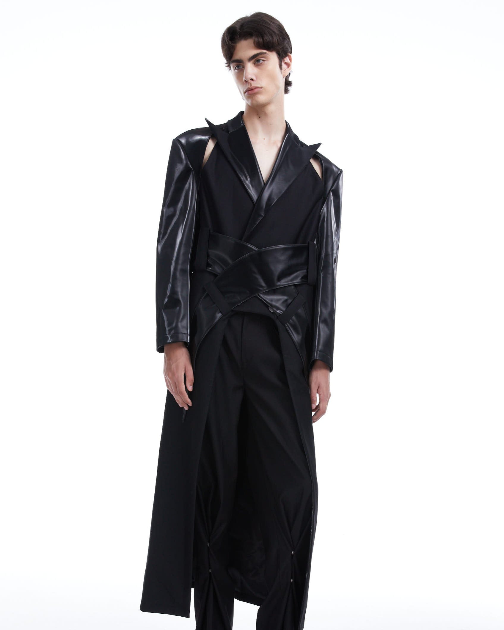 Person wearing a black outfit with glossy texture on a white background