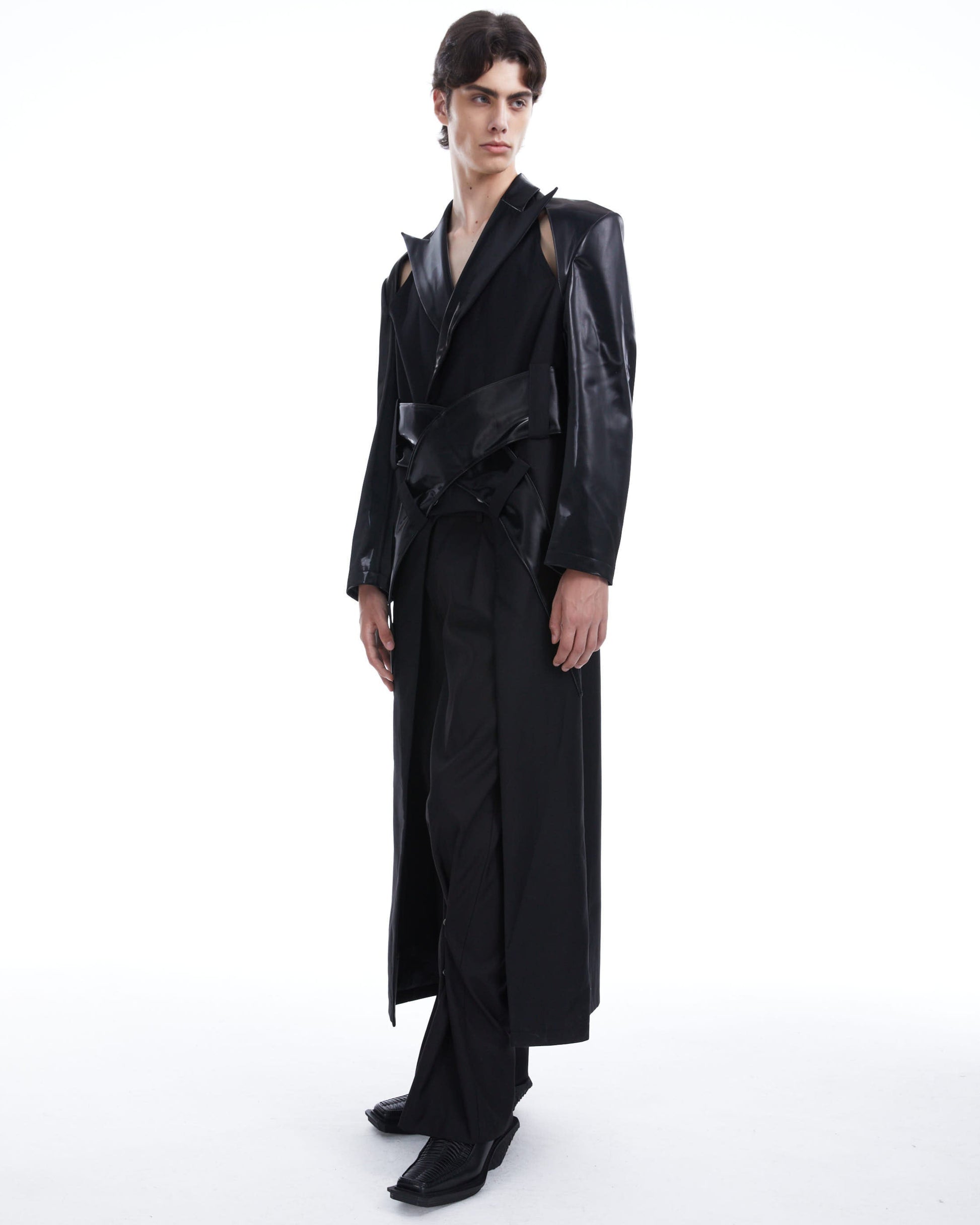 Person wearing a long black coat on a white background
