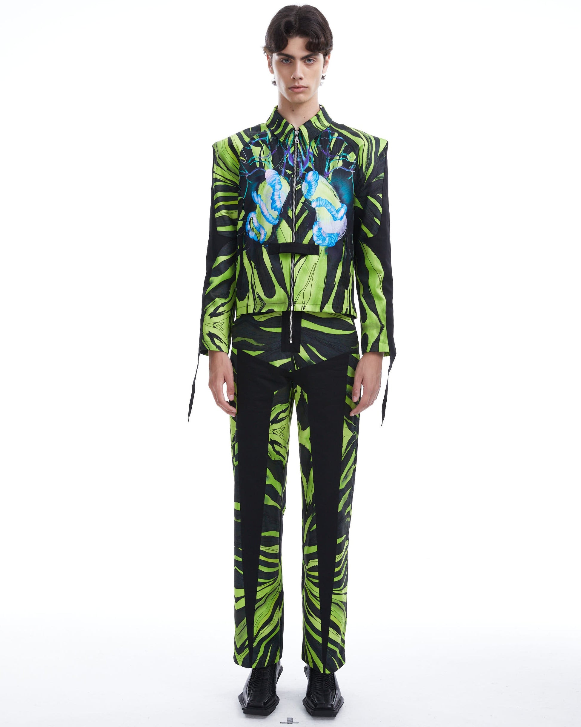 Person wearing a green and black patterned outfit on a white background
