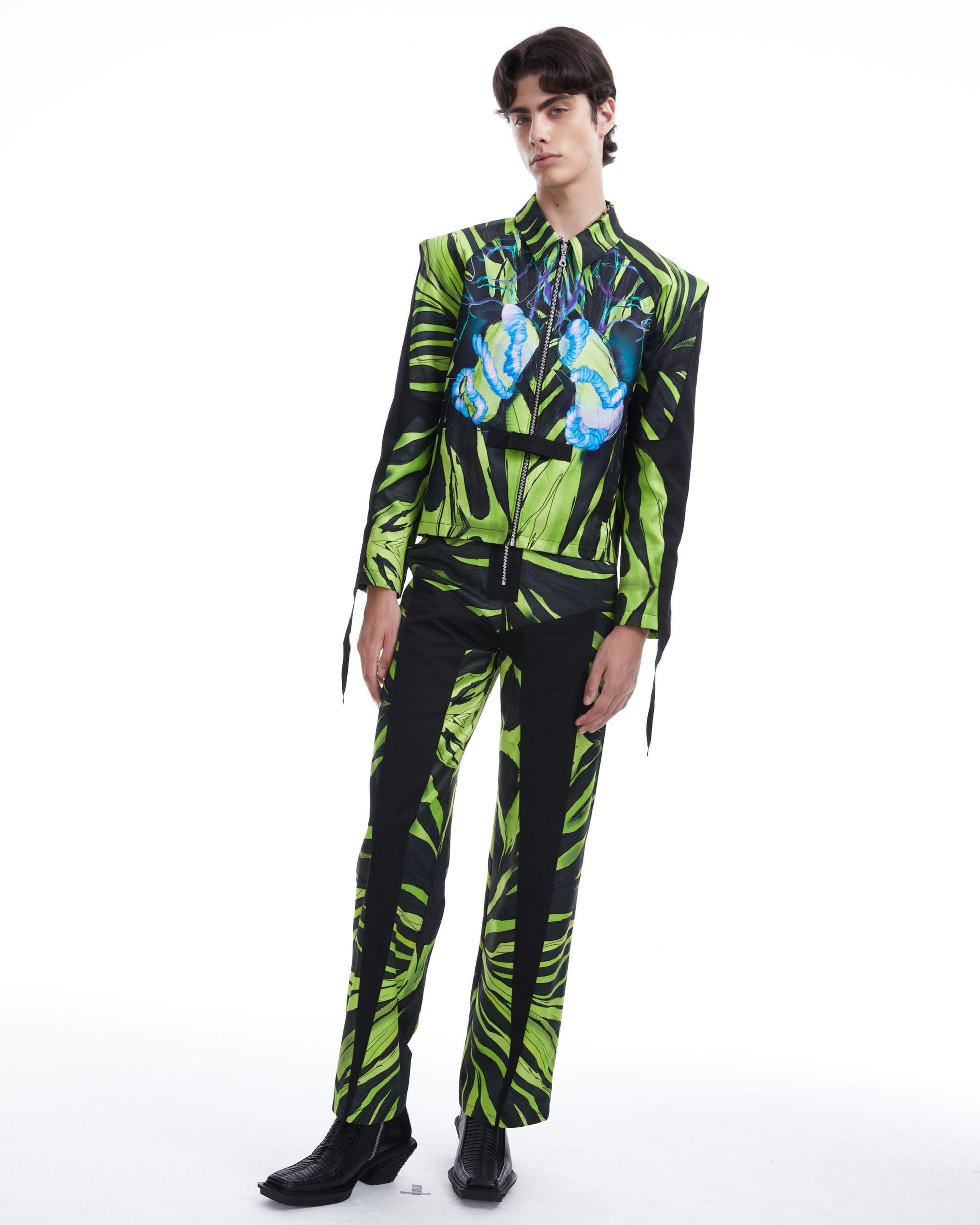 Person wearing a green and black patterned outfit on a white background